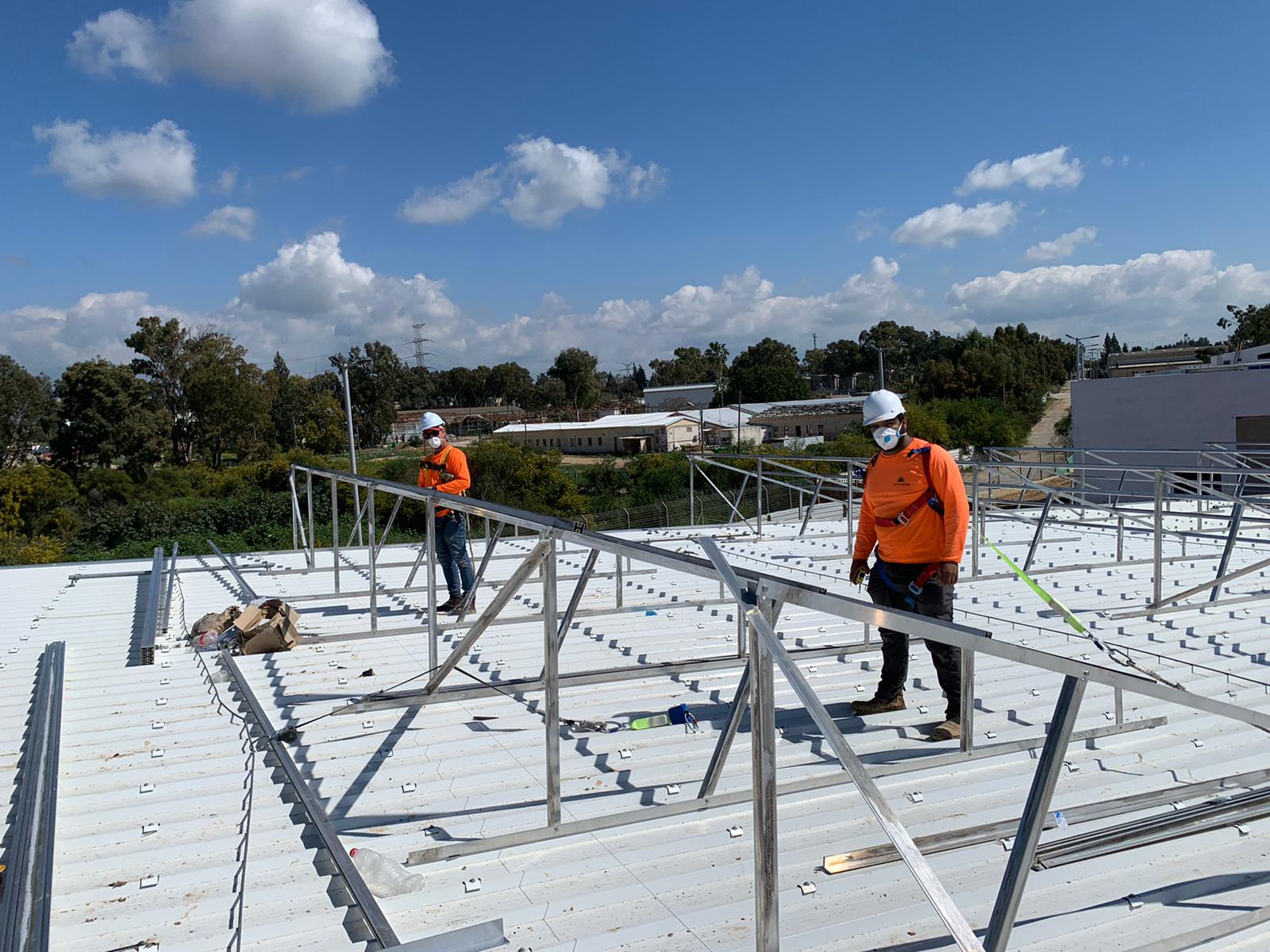 עובדי חברת קדמה סולארי מתקינים מערכת על תשתית גג מסחרי עשוי אזכורית